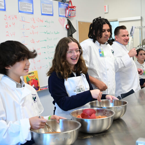 Emeril’s Culinary Garden & Teaching Kitchen students cooking in school kitchen.