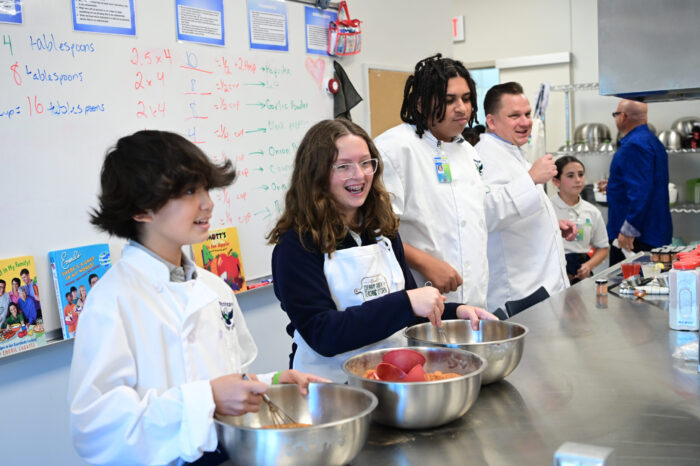 Emeril’s Culinary Garden & Teaching Kitchen students cooking in school kitchen.