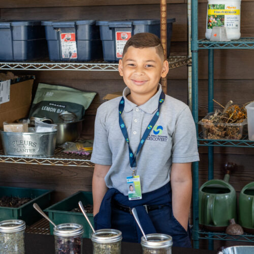 Student smiling and learning in an outdoor classroom.